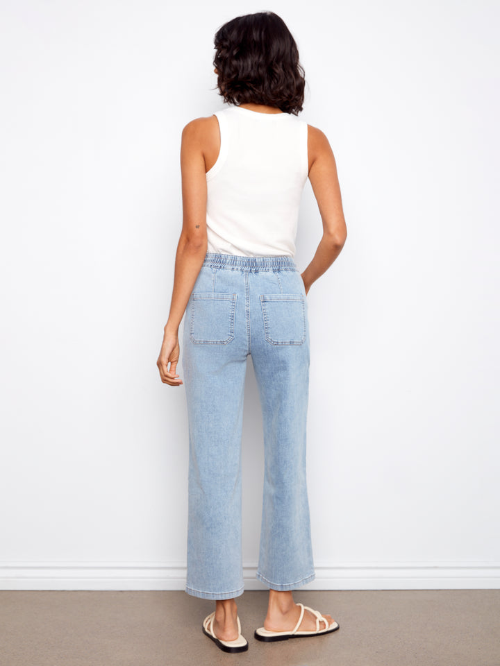 Woman wearing light blue jeans and a white top against a white background