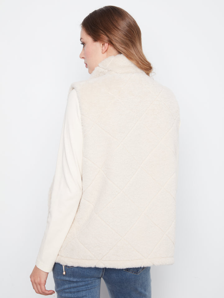 A woman shown from the back wearing a cream-colored, diamond-quilted faux-fur vest over a matching cream long-sleeve top and blue jeans, set against a plain white studio background.