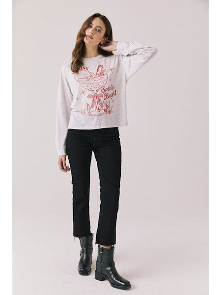Woman wearing a white sweatshirt with a graphic design on a plain background