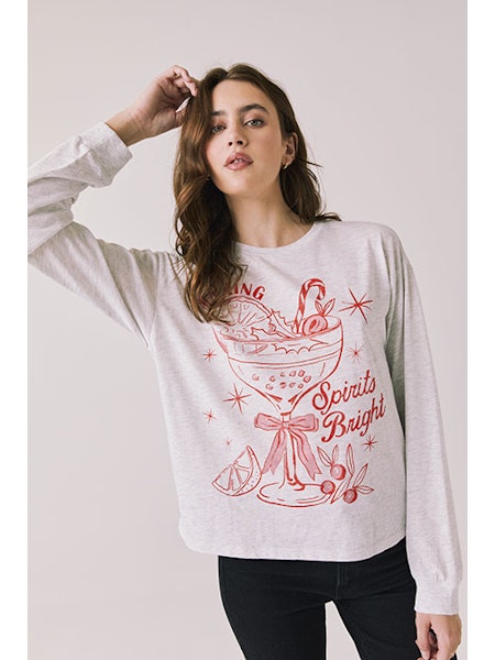 Woman wearing a white sweatshirt with red graphic design on a plain background