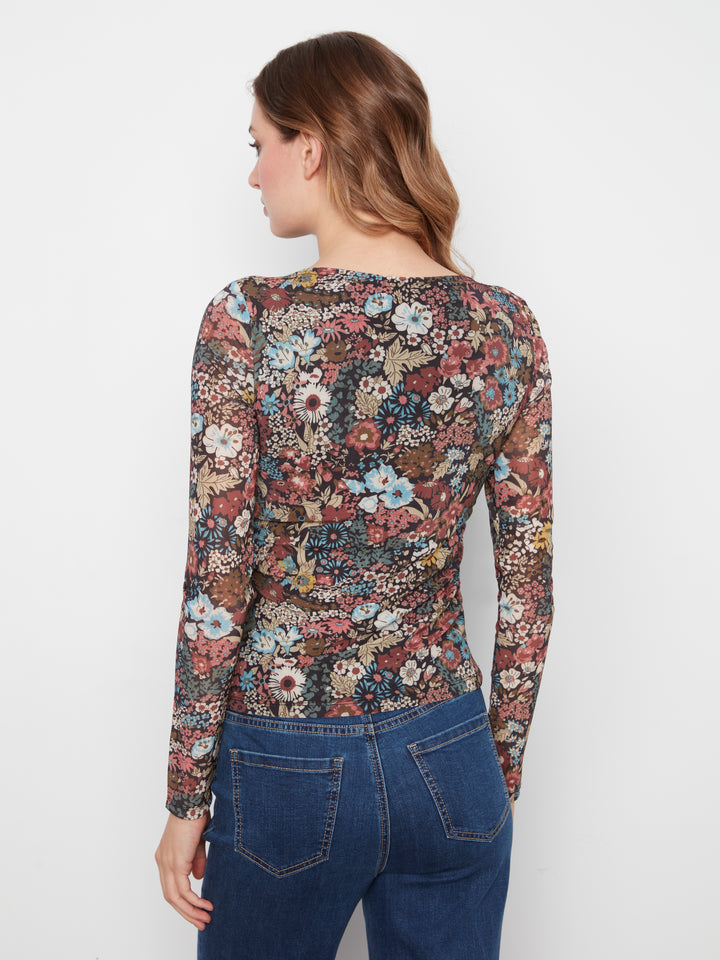 Woman wearing a floral long-sleeve top and blue jeans against a white background