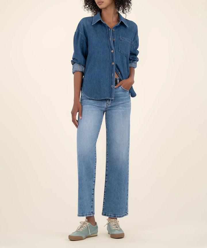 Person wearing a blue denim shirt and jeans on a beige background