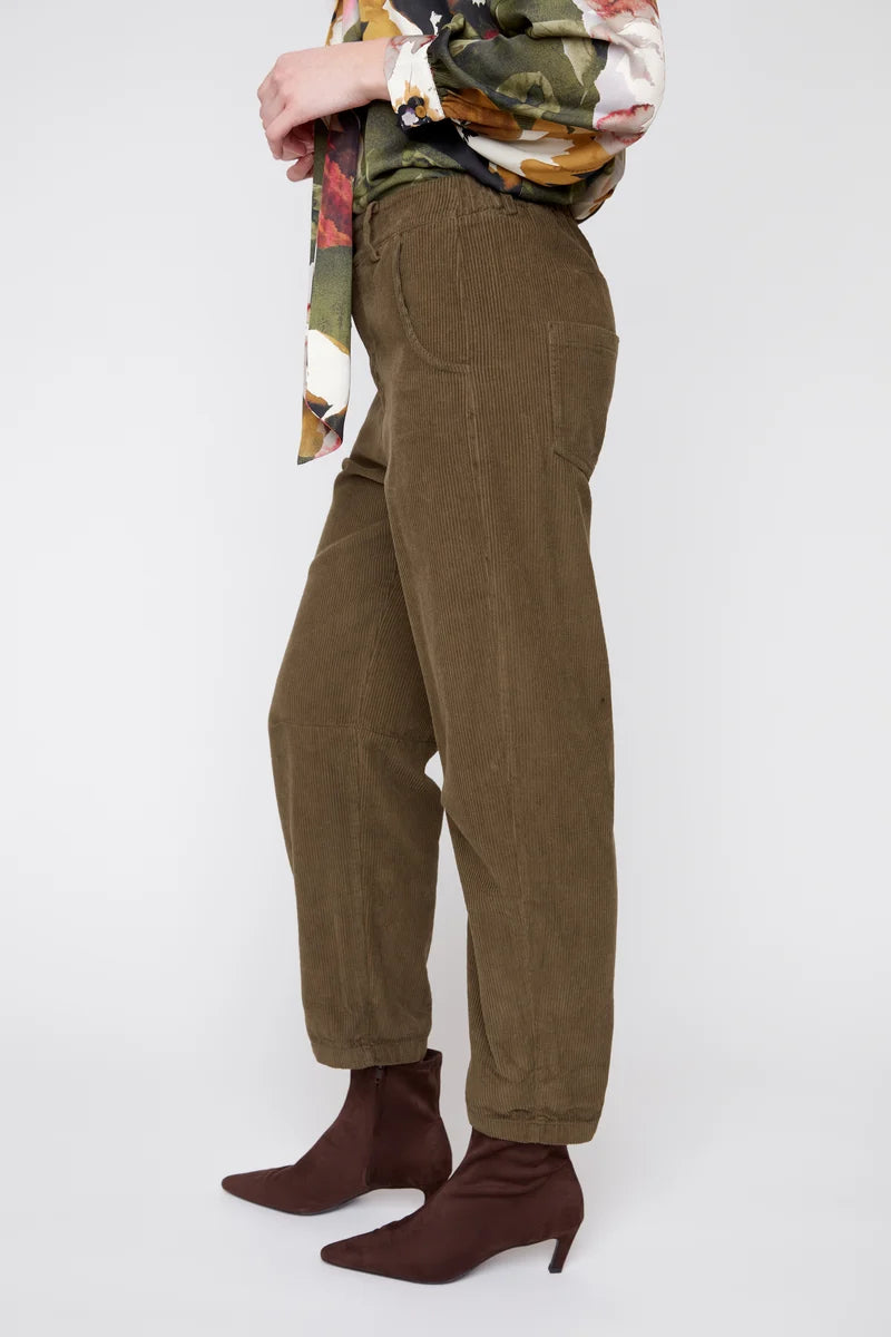 Person wearing brown corduroy pants and brown boots on a white background