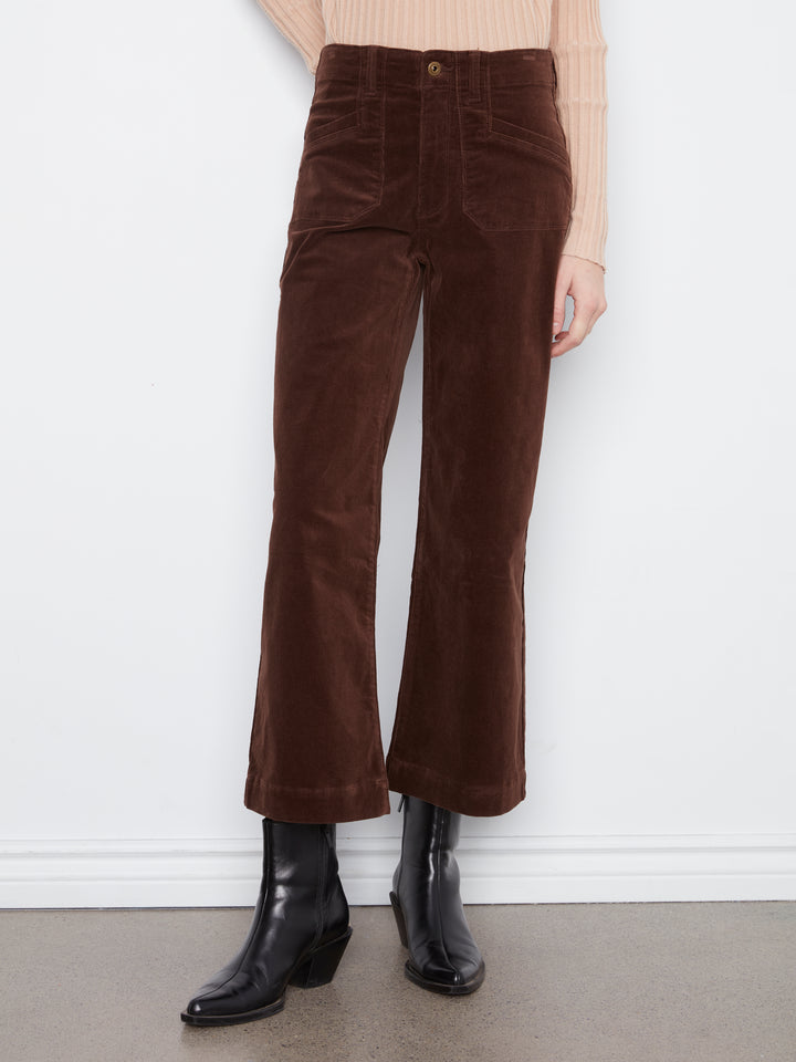 Brown corduroy pants worn by a person against a white wall.
