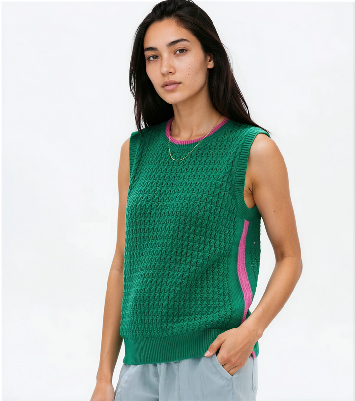 Woman wearing a green sleeveless knitted top with pink trim on a white background