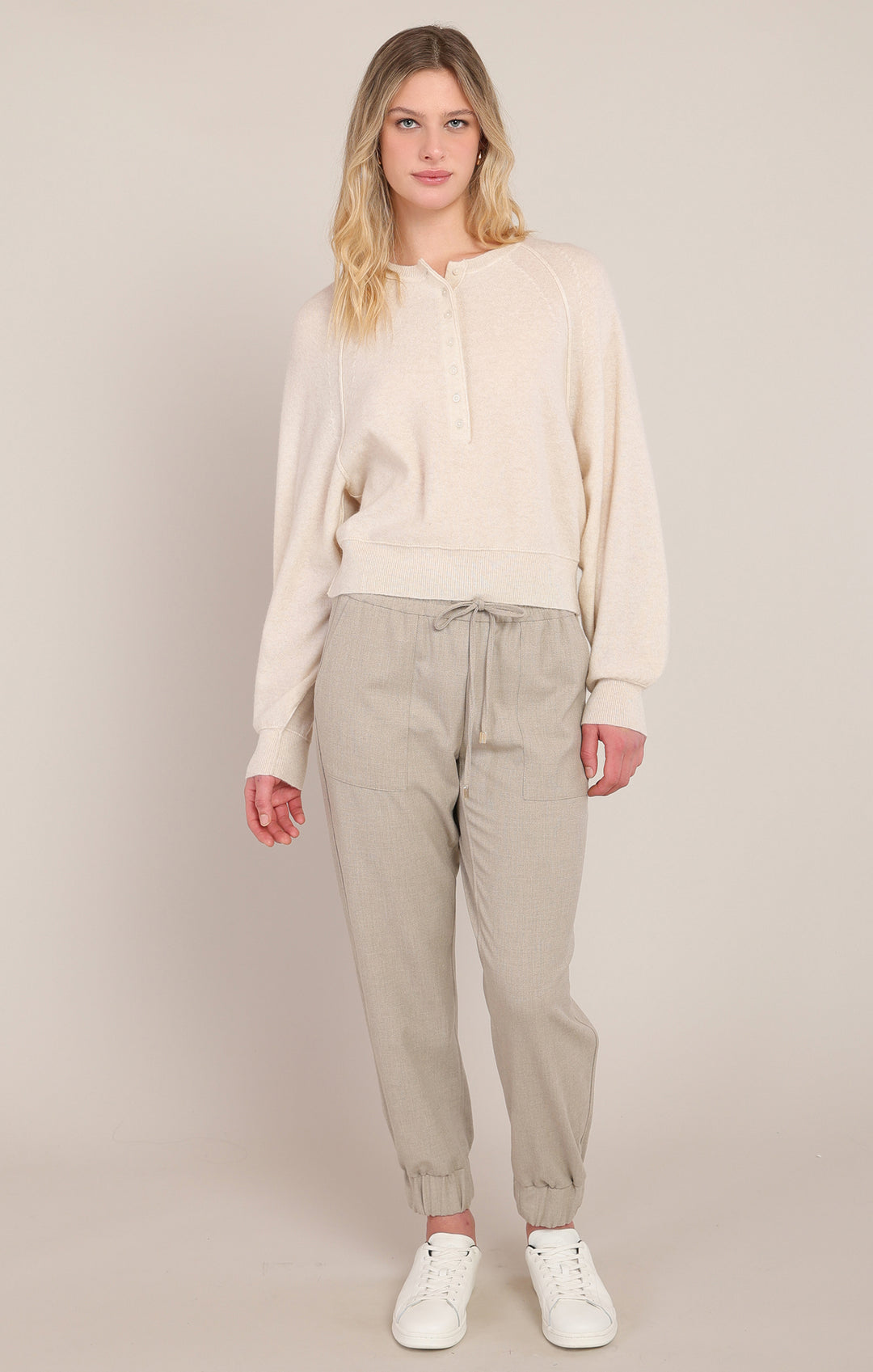 Woman wearing a beige outfit with a plain background