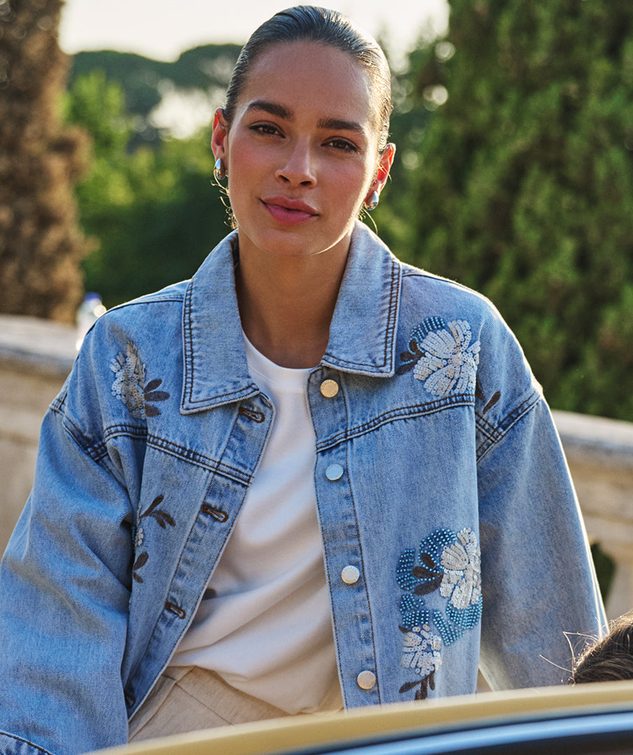 Woman wearing a blue denim jacket with floral embroidery outdoors