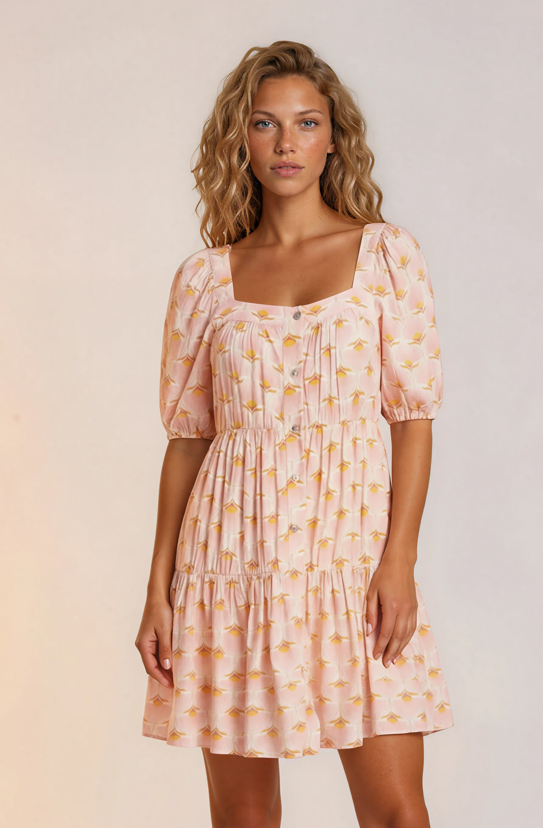 Woman wearing a pink patterned dress with puff sleeves against a plain background