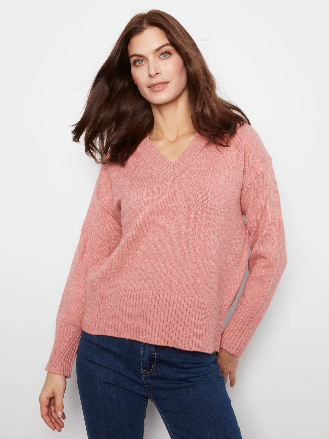 Woman wearing a pink sweater and blue jeans on a white background