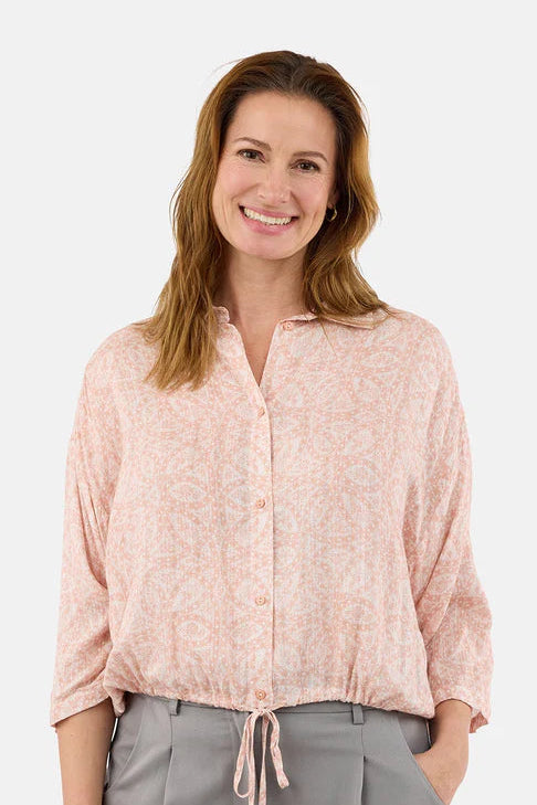 Woman wearing a light pink blouse with a subtle pattern on a white background