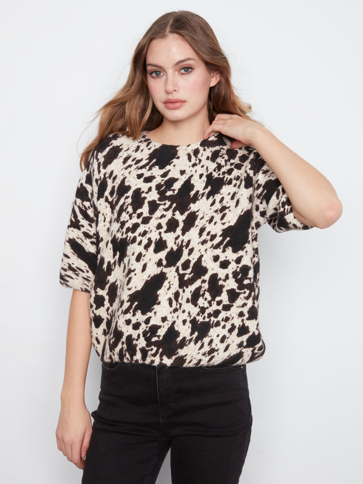 Woman wearing a black and white patterned top against a white background