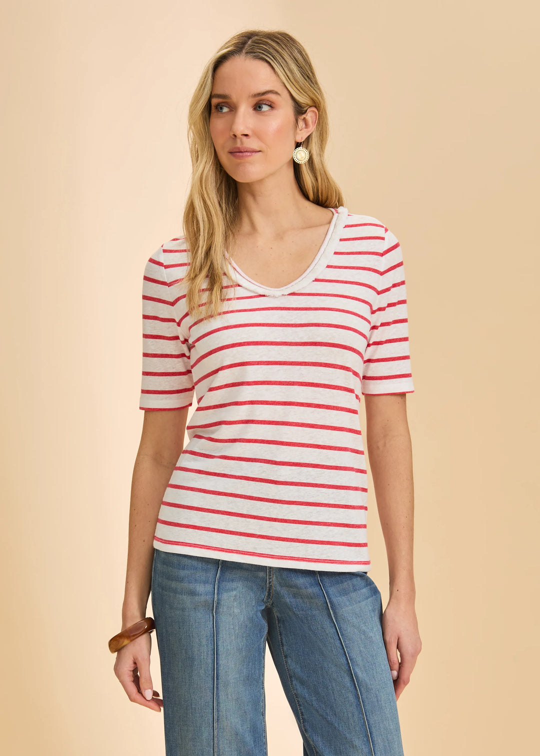 Woman wearing a red and white striped shirt with blue jeans on a beige background