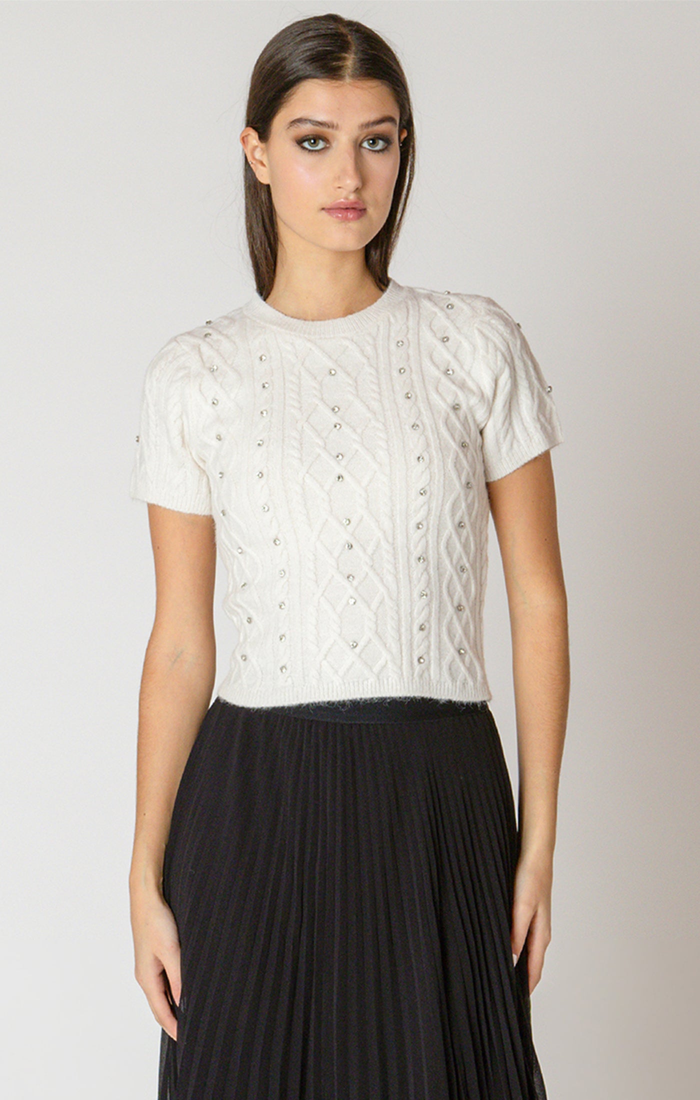 Woman wearing a white lace top and black skirt on a plain background