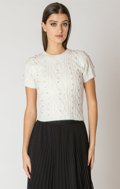 Woman wearing a white lace top and black skirt on a plain background