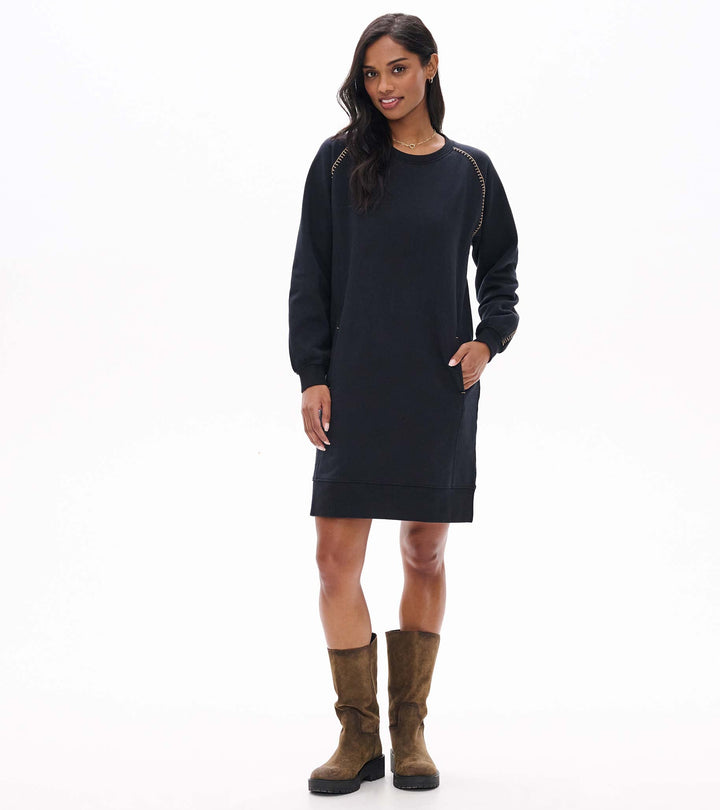 Woman wearing a black dress and brown boots on a white background