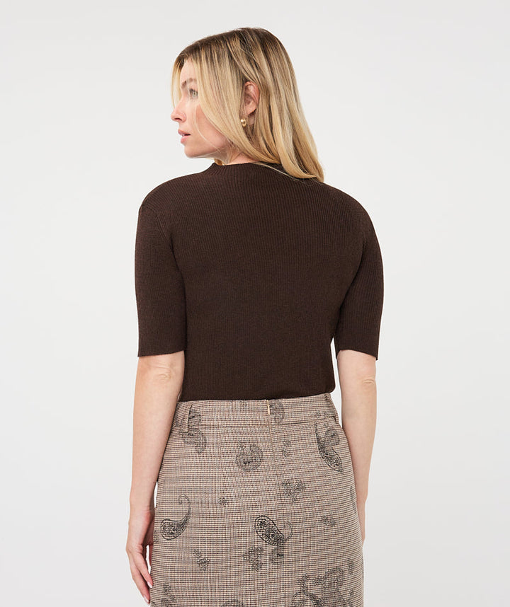 A woman shown from the back wearing a dark brown short-sleeve knit top and a beige plaid skirt with black paisley patterns, against a plain white studio background.