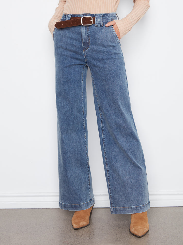 Person wearing blue jeans with a belt against a white background
