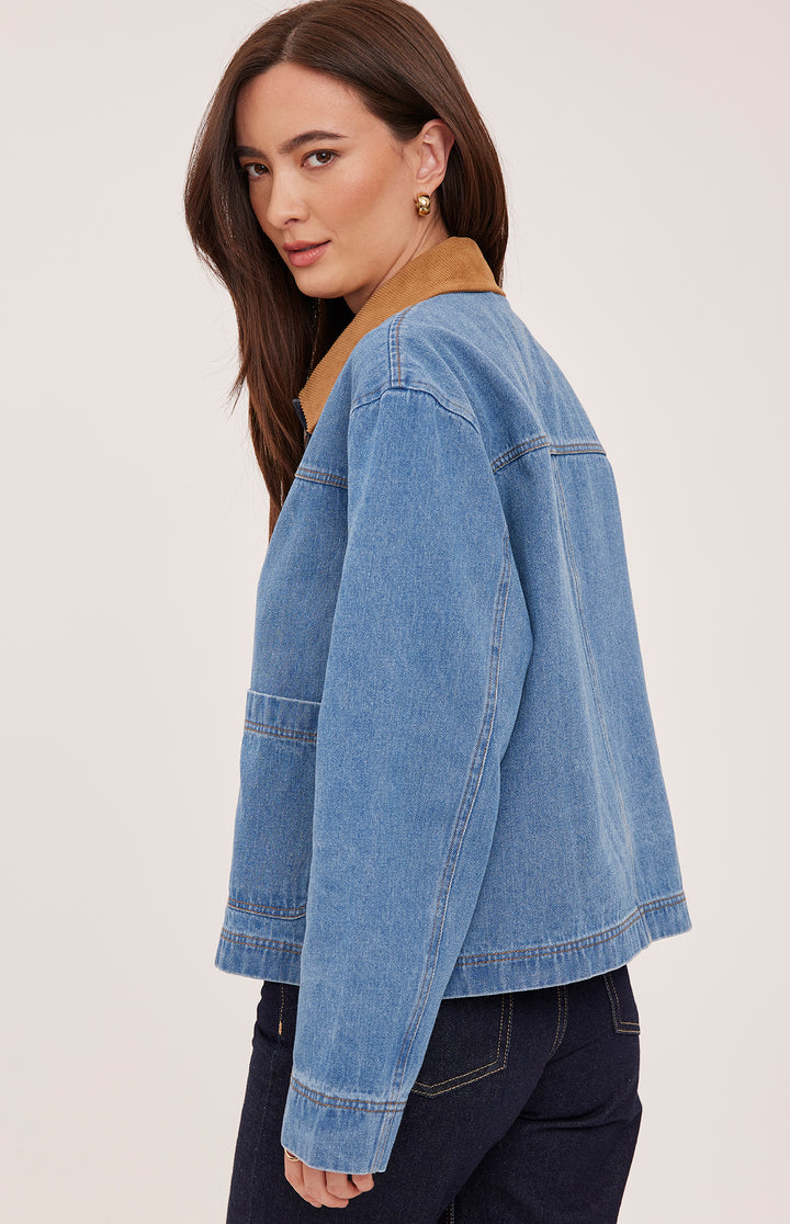 Woman wearing a blue denim jacket on a plain background