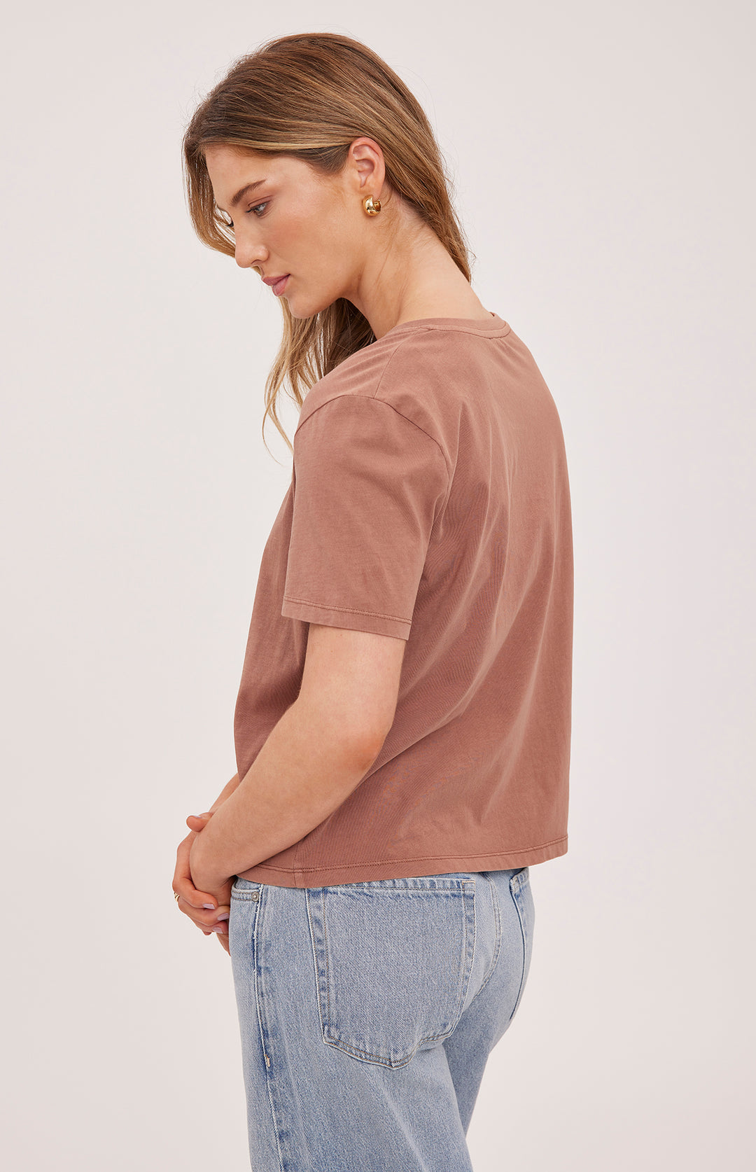 Woman wearing a brown t-shirt and blue jeans on a white background