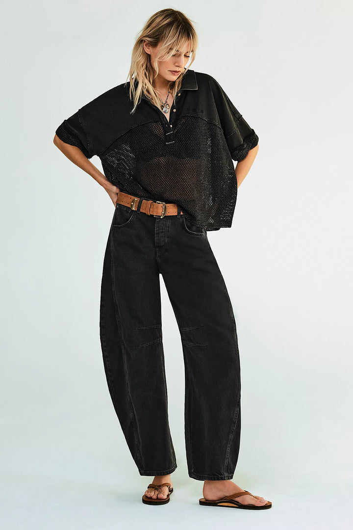 Person wearing a black outfit with a sheer top and wide-leg pants on a white background