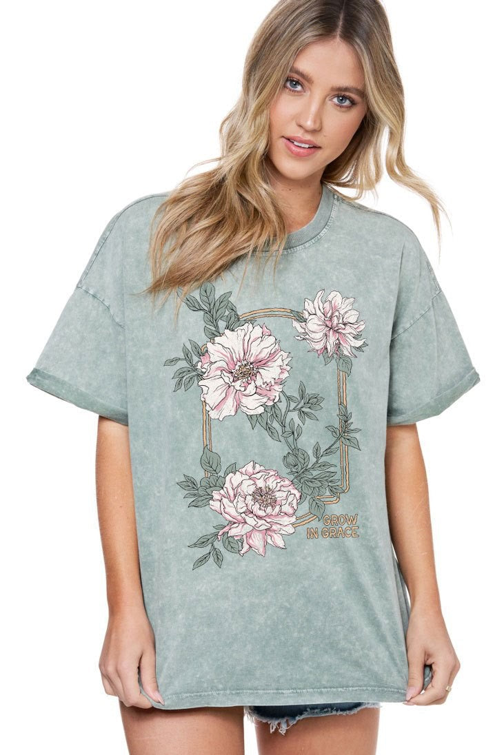 Woman wearing a light green t-shirt with floral designs on a white background