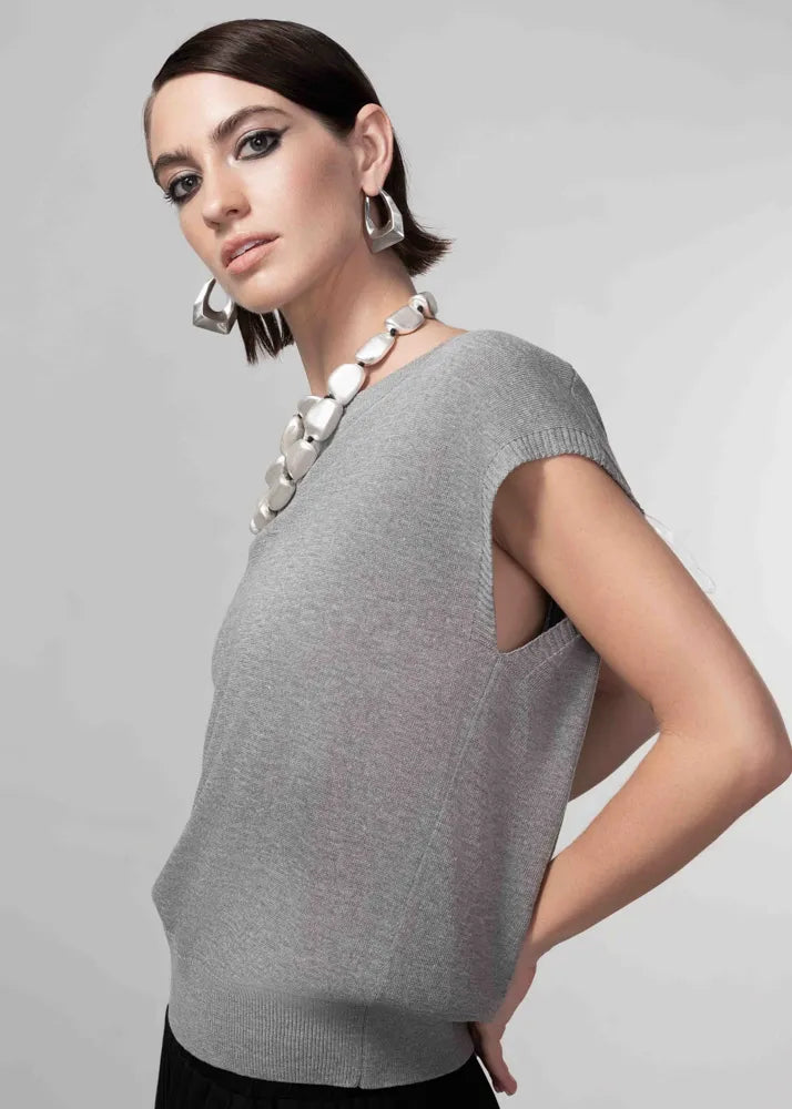 Woman wearing a gray sweater with a plain background