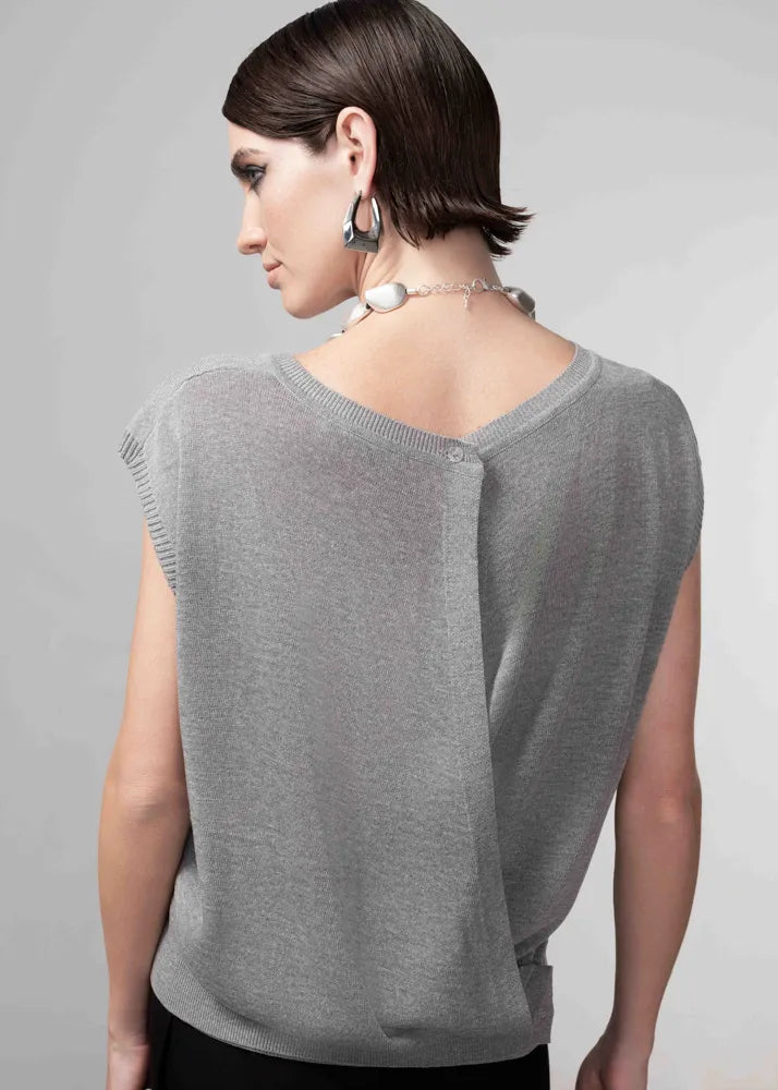 Woman wearing a gray sleeveless top against a plain background