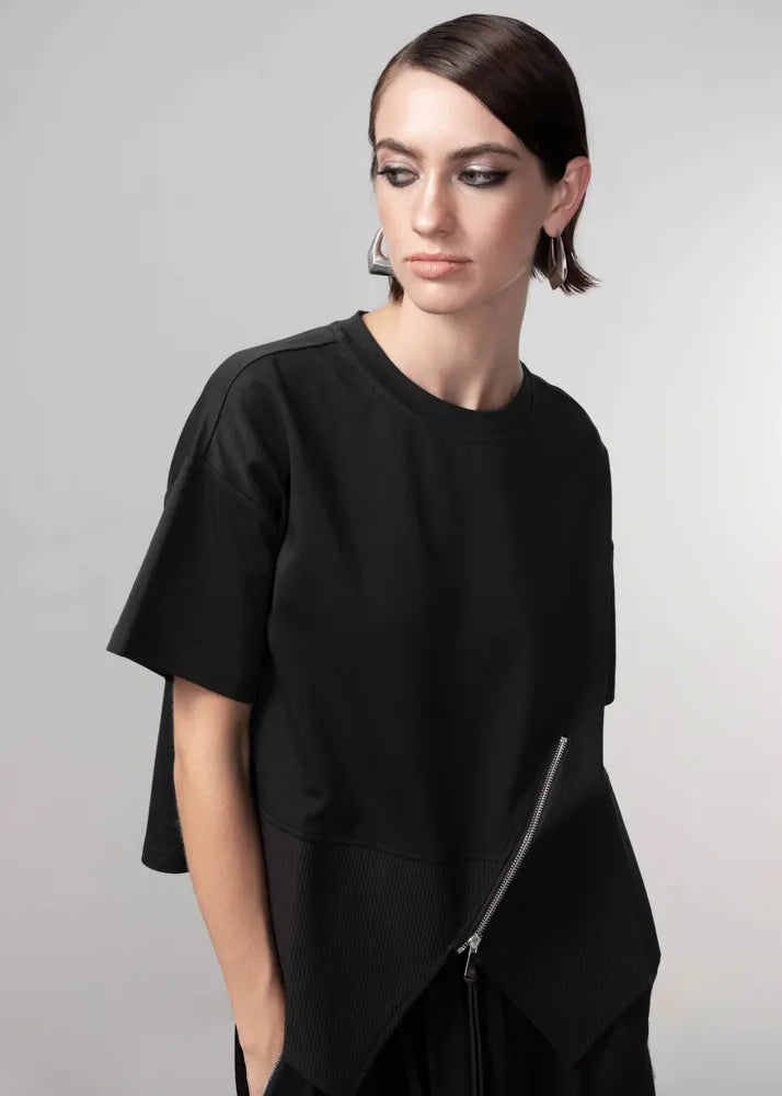 Woman wearing a black outfit with a zipper on a gray background