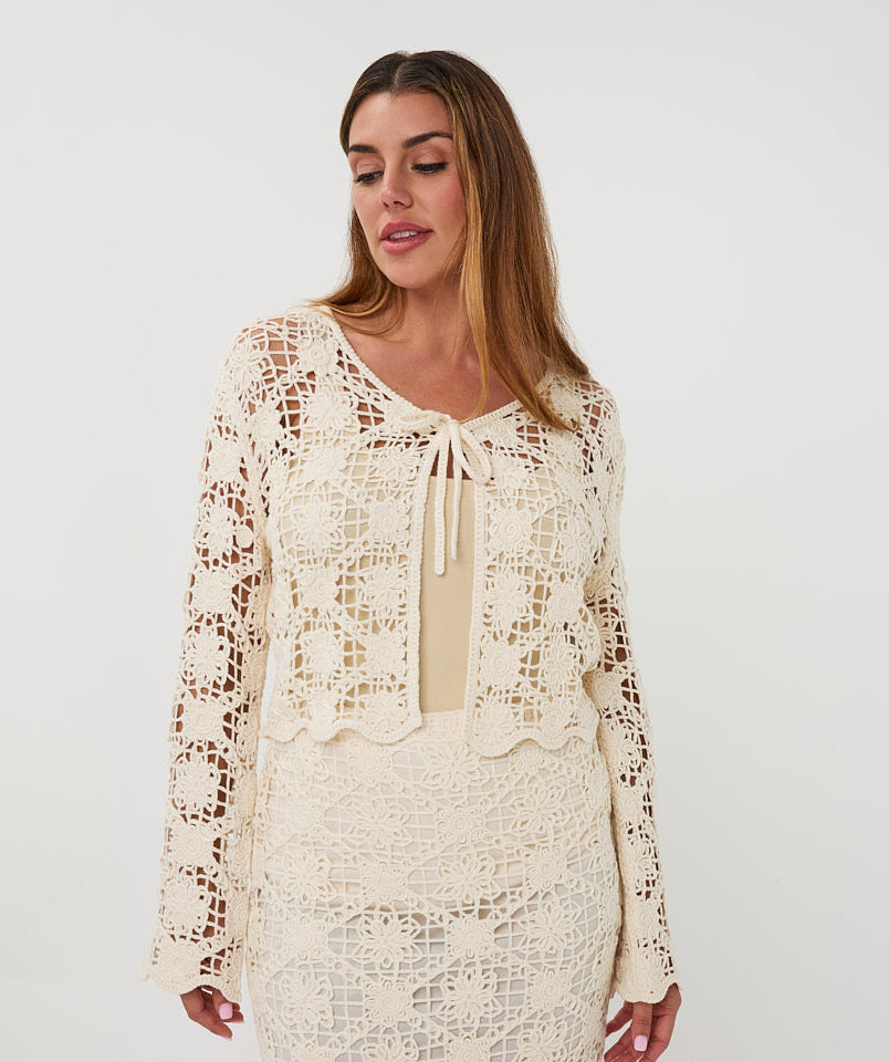 Woman wearing a cream lace outfit on a white background