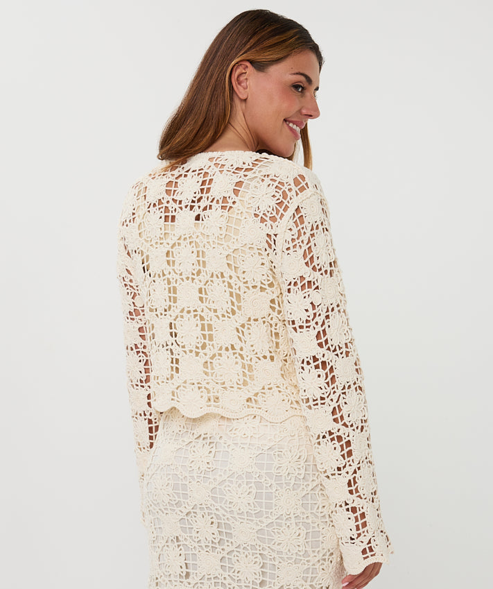 Woman wearing a white lace outfit against a plain background