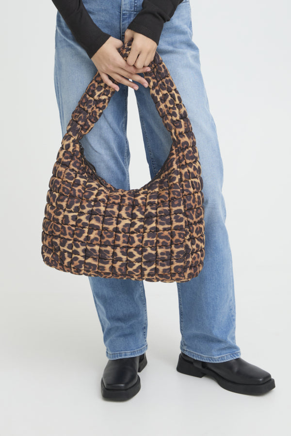 Person holding a leopard print handbag against a white background
