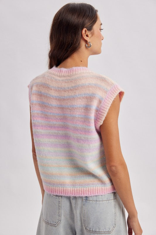 Woman wearing a pastel striped sleeveless sweater against a plain background