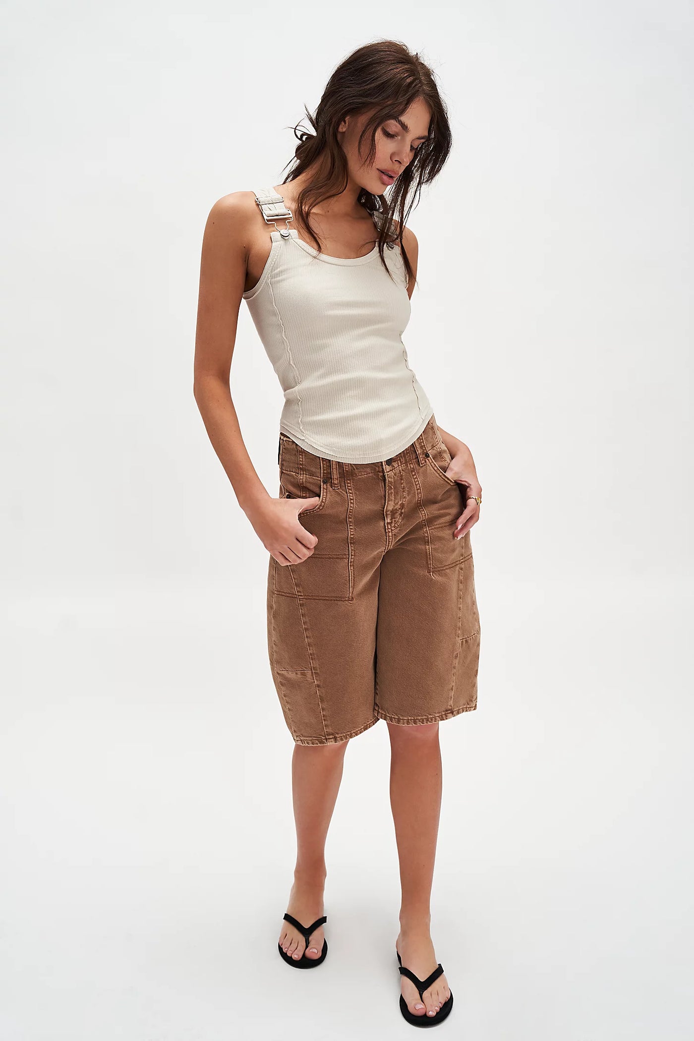 Woman wearing a white tank top and brown shorts on a white background