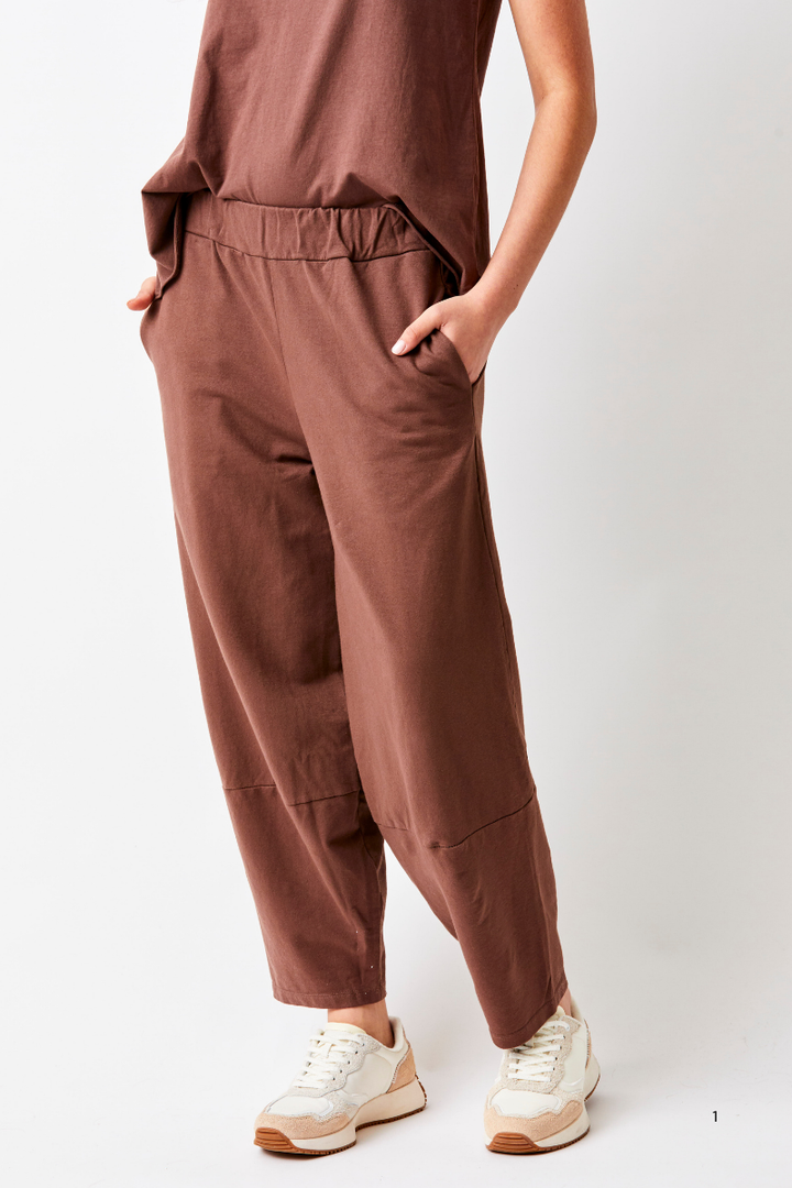 Person wearing brown pants and white sneakers on a white background