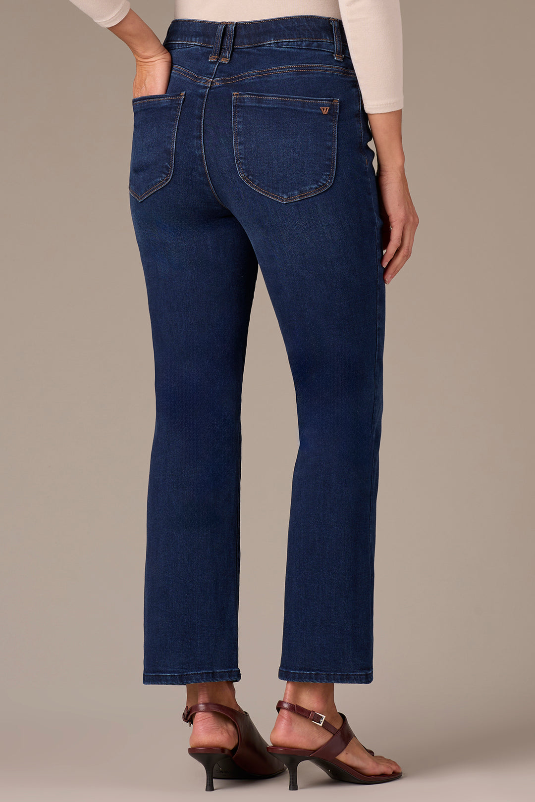 Blue jeans worn by a person on a beige background
