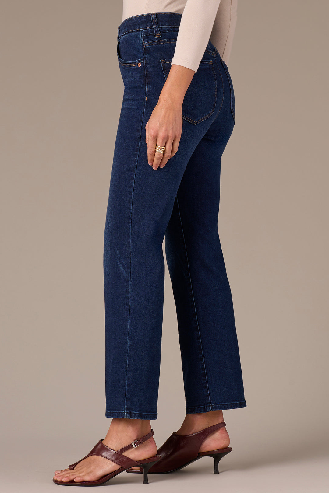 Person wearing dark blue jeans on a neutral background