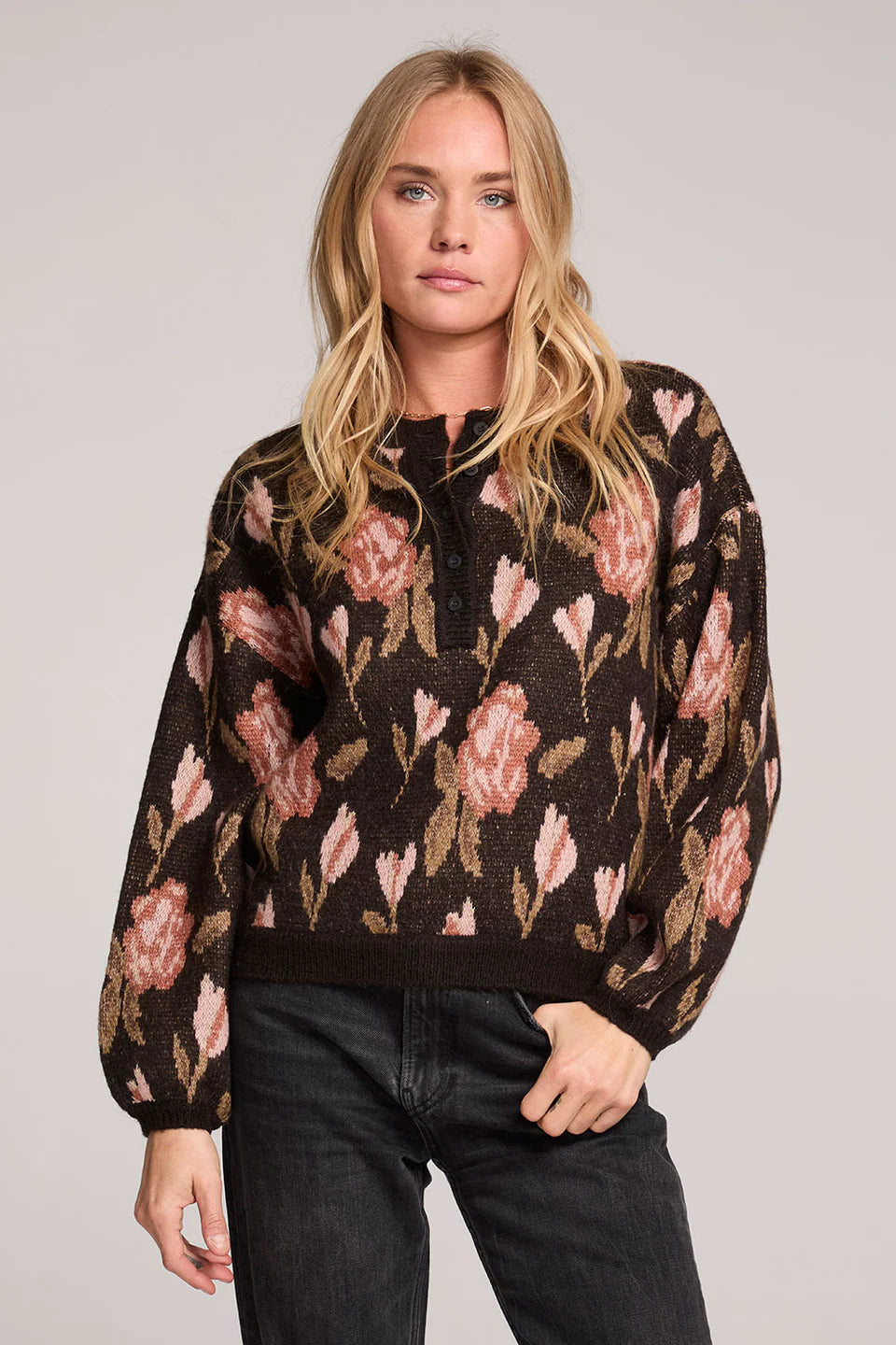 Woman wearing a floral-patterned sweater against a plain background