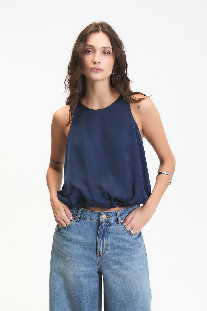 Woman wearing a blue sleeveless top and jeans on a white background