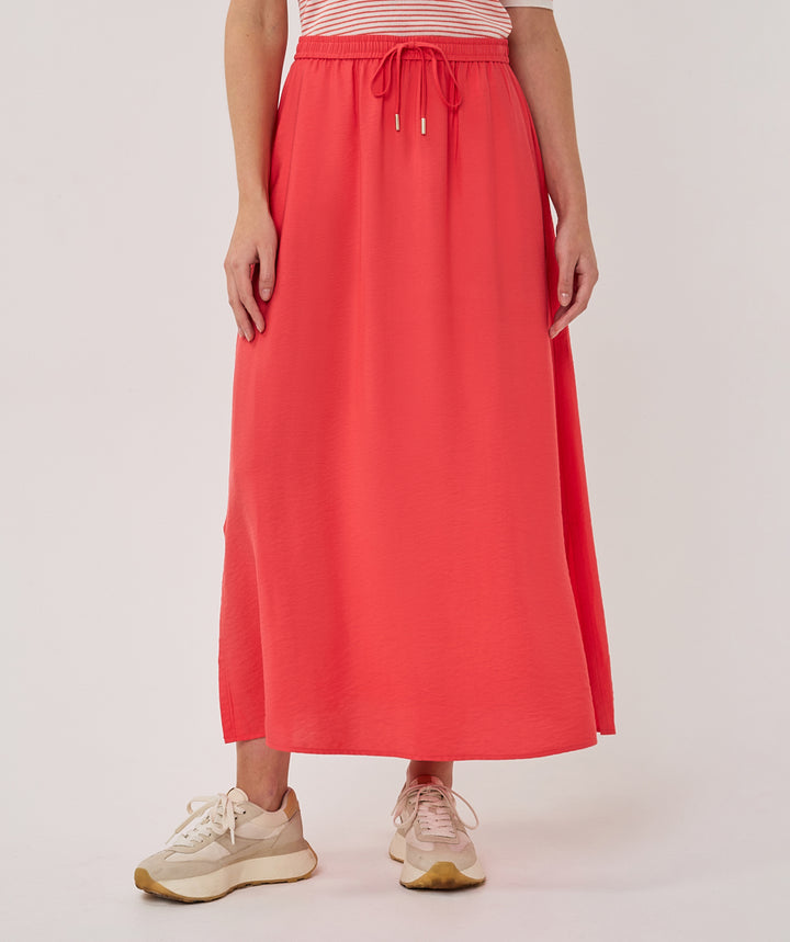Person wearing a coral skirt with a white background