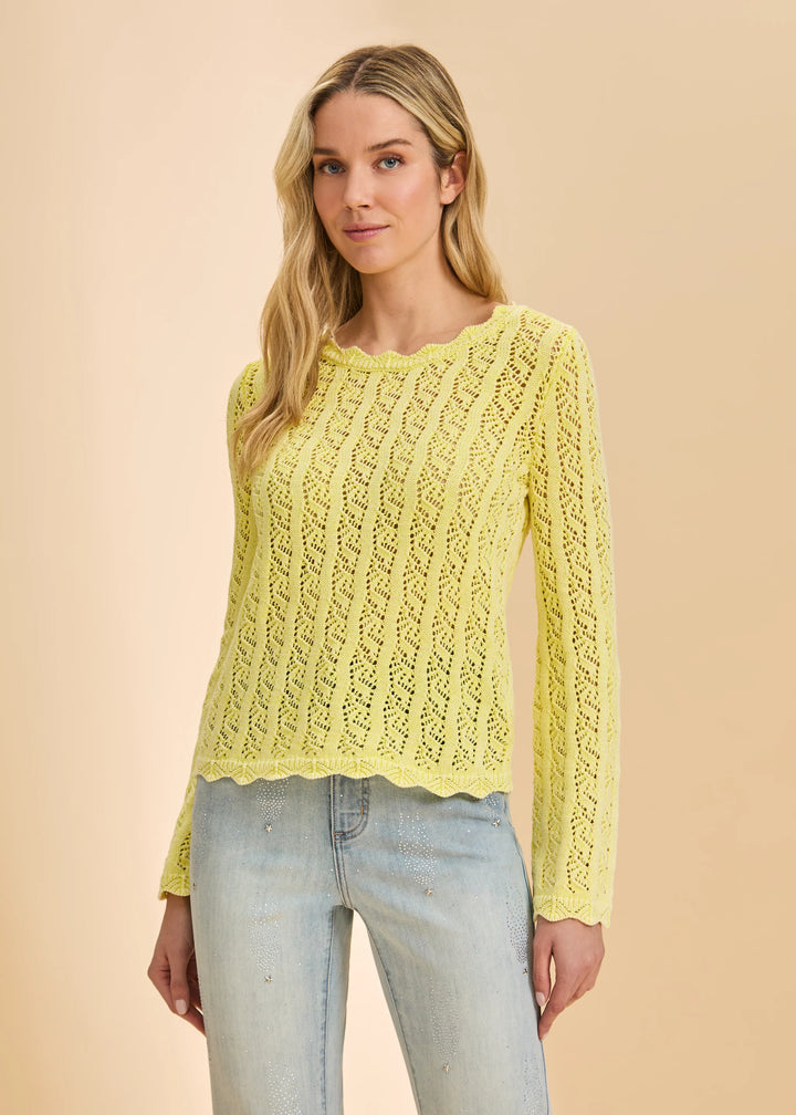 Woman wearing a yellow lace sweater against a beige background