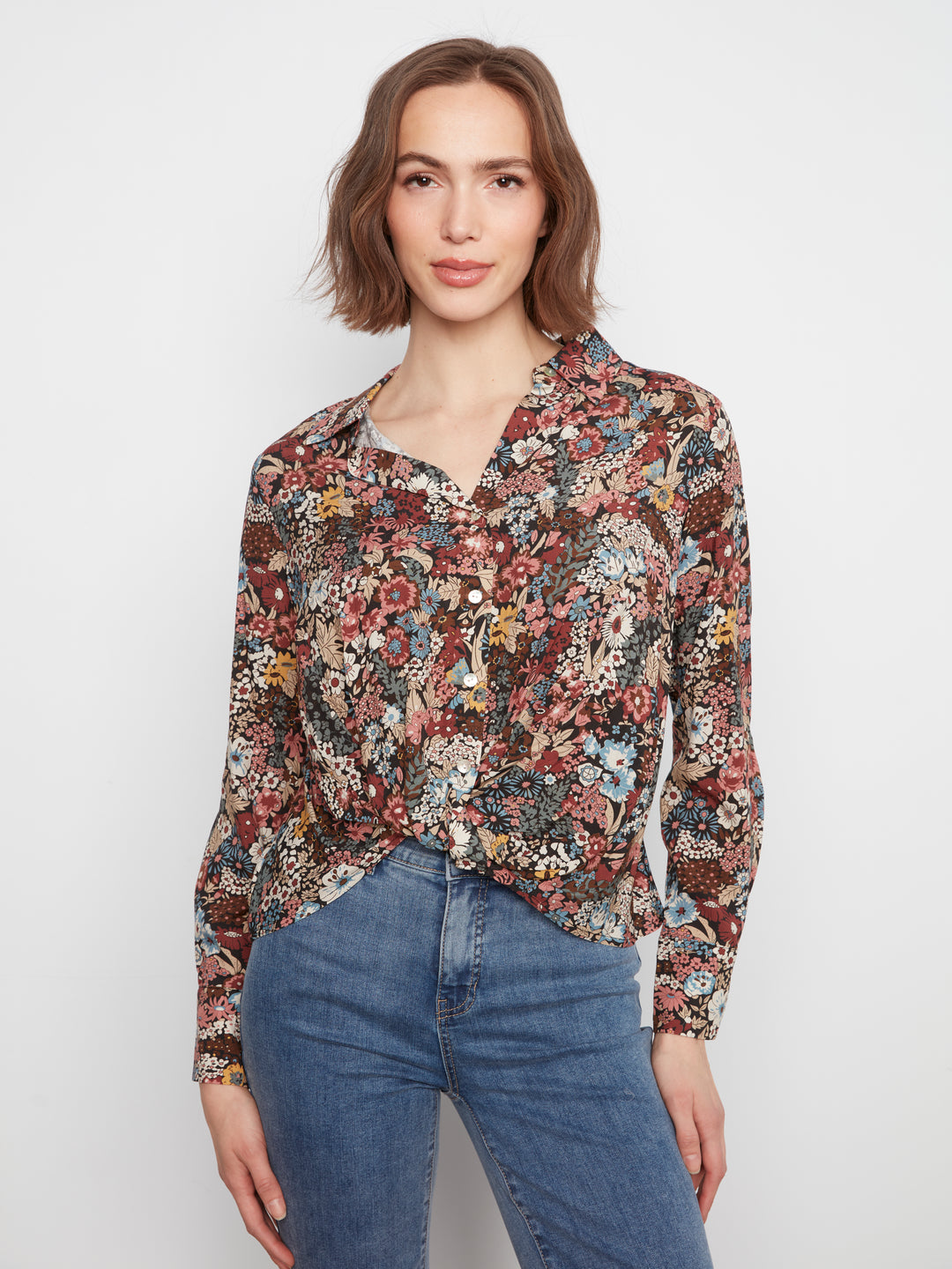 Woman wearing a floral blouse and jeans on a white background