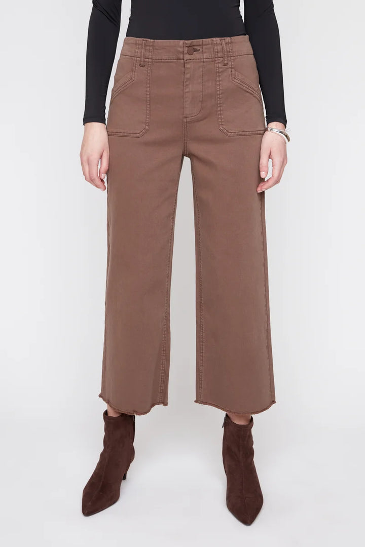 A model wearing brown wide-leg cropped pants with a black long-sleeve top and dark brown pointed-toe ankle boots, shown from the waist down against a light gray studio background.