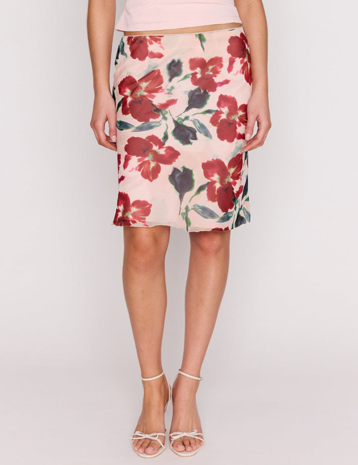 Woman wearing a pink sleeveless top and floral skirt on a white background
