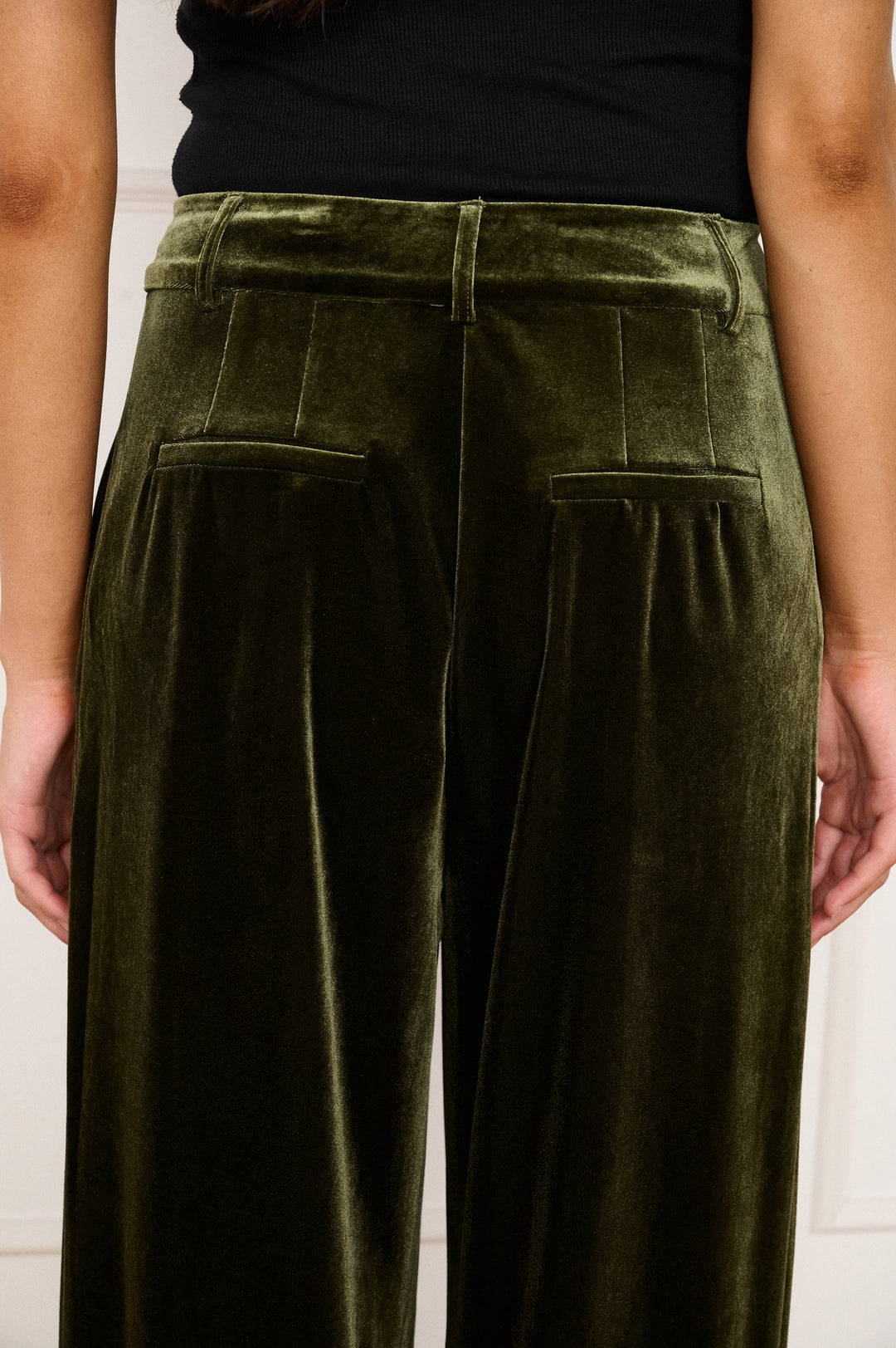 Green velvet pants worn by a person on a white background