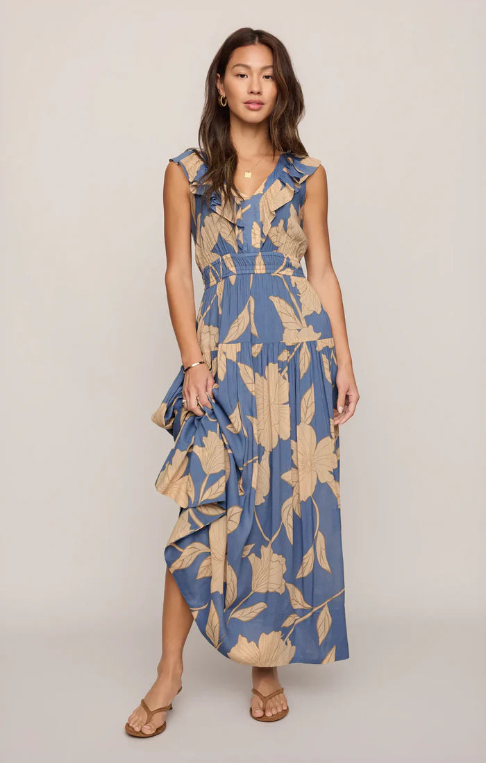 Woman wearing a blue and beige floral dress on a plain background