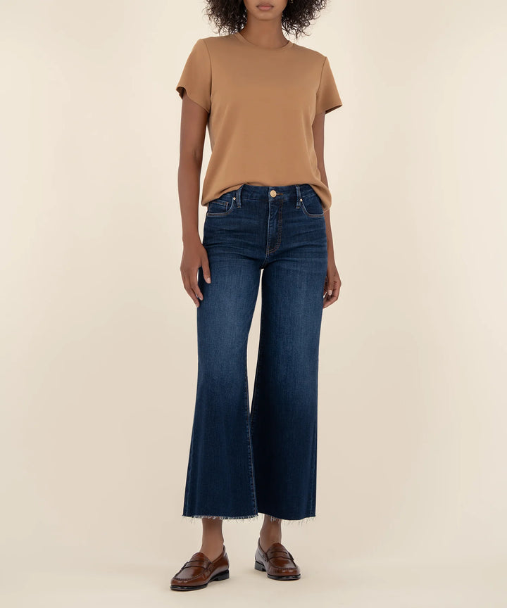 Person wearing a brown t-shirt and blue jeans on a beige background