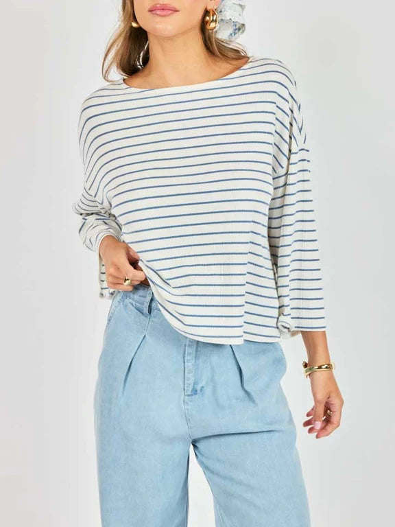 Woman wearing a striped long-sleeve top and light blue jeans on a white background