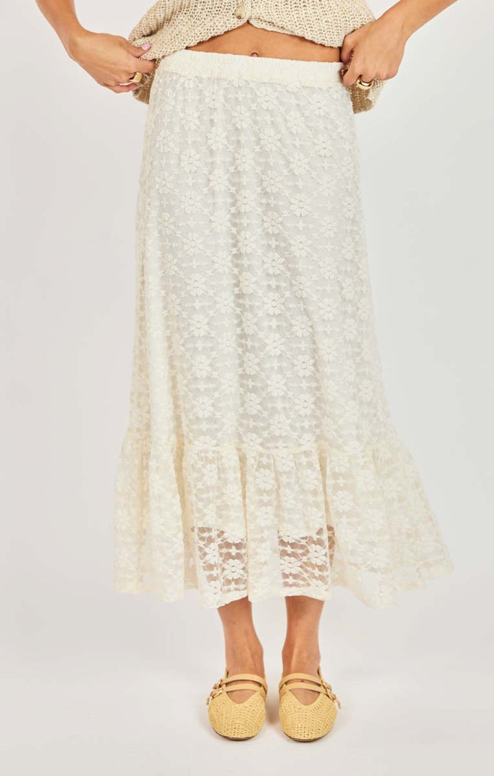 Person wearing a white lace skirt with a plain background
