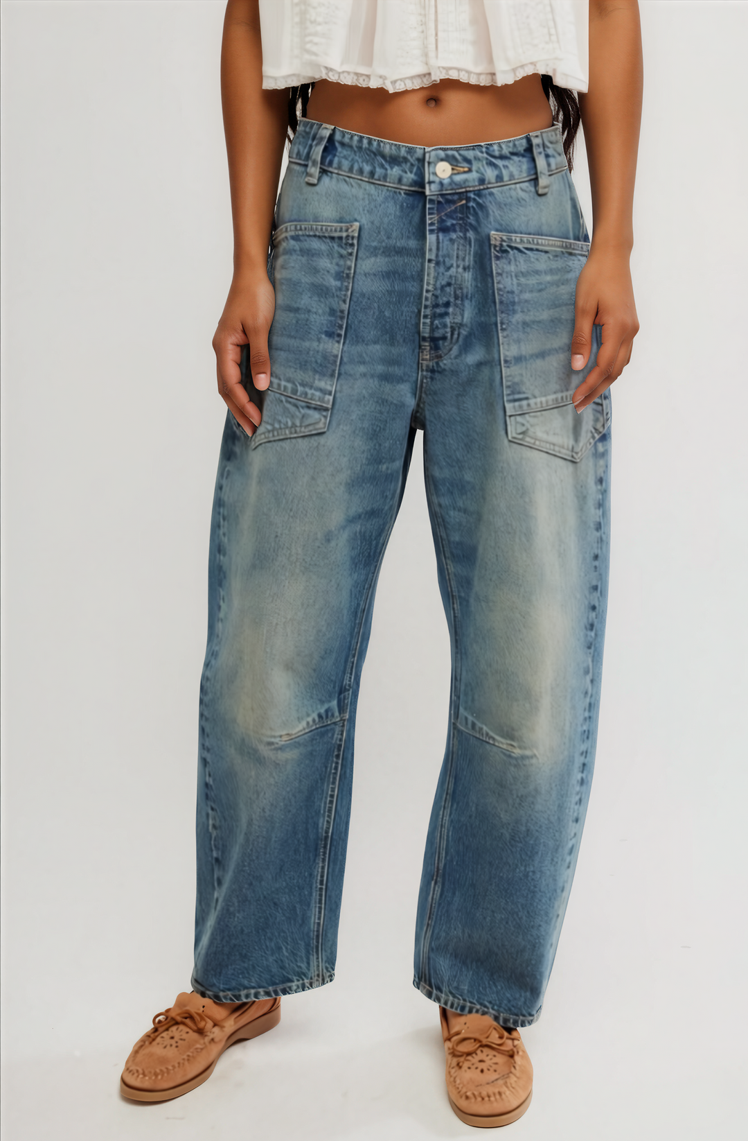 Person wearing blue jeans and brown shoes on a plain background