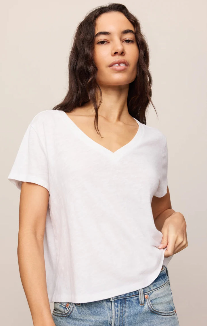 Woman wearing a plain white t-shirt and blue jeans against a beige background